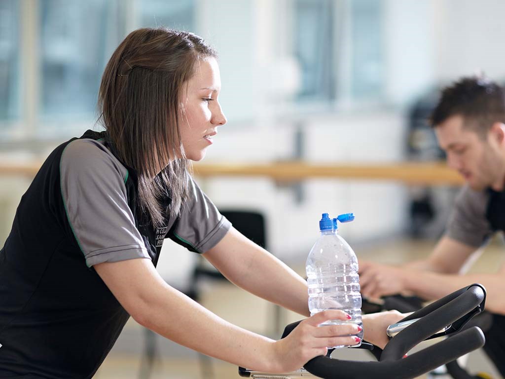person using gym equipment holding water bottle