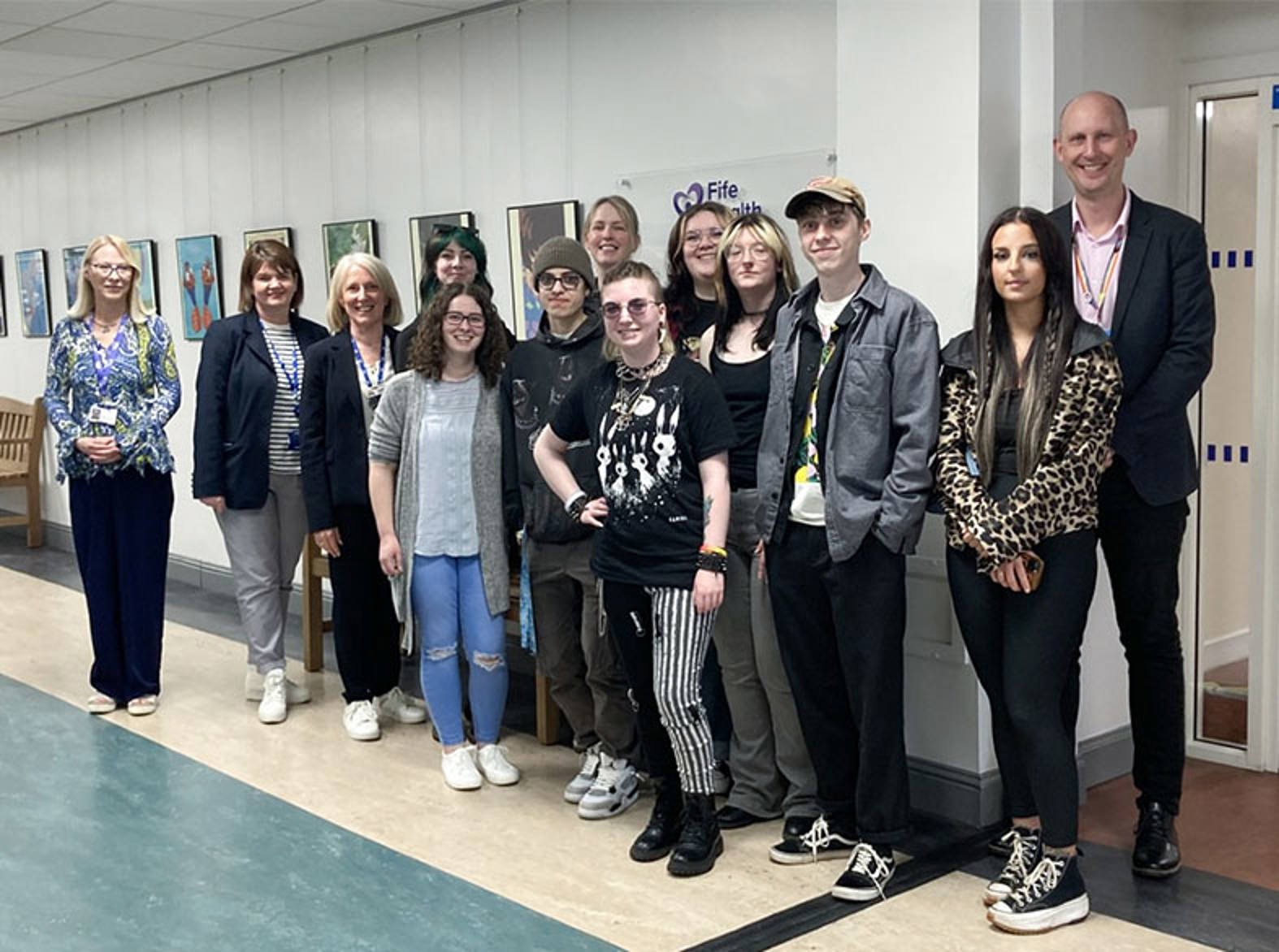 A group of people standing in front of a wall of art 