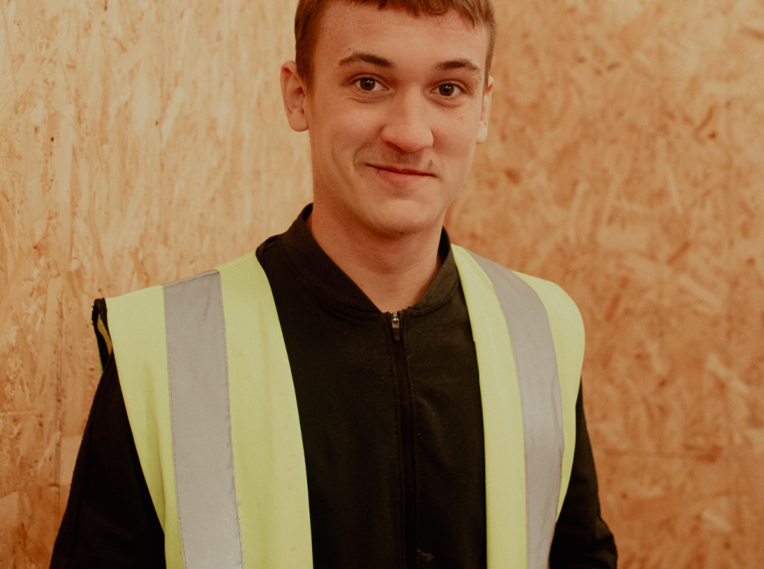 male modern apprentice wearing a high vis jacket smiling at camera