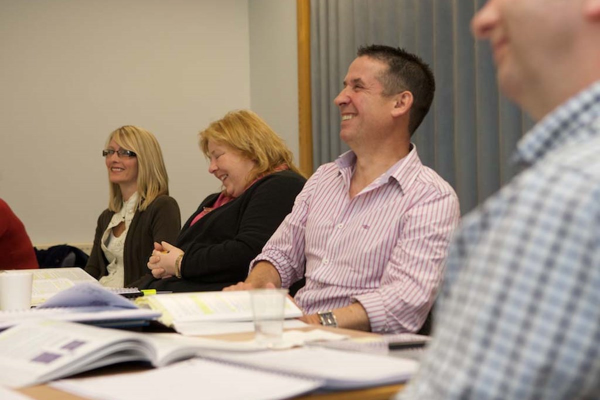 group of adult learners laughing and smiling whilst learning 