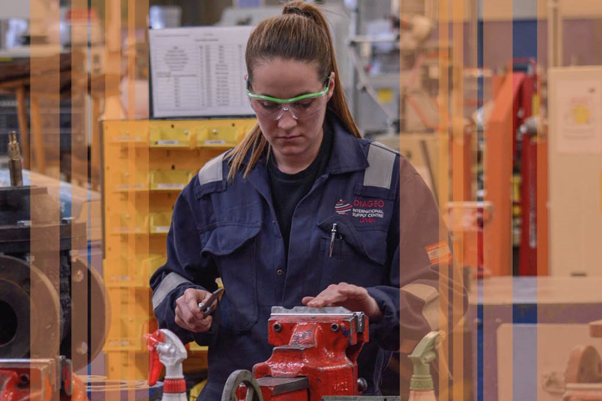 engineering student working on engineering equipment wearing goggles and overalls with orange stripes on top of image