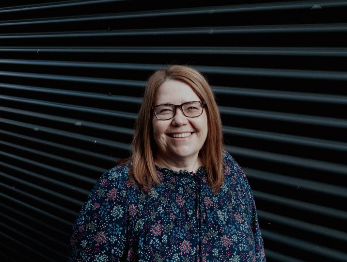 female staff member with glasses smiling at camera 