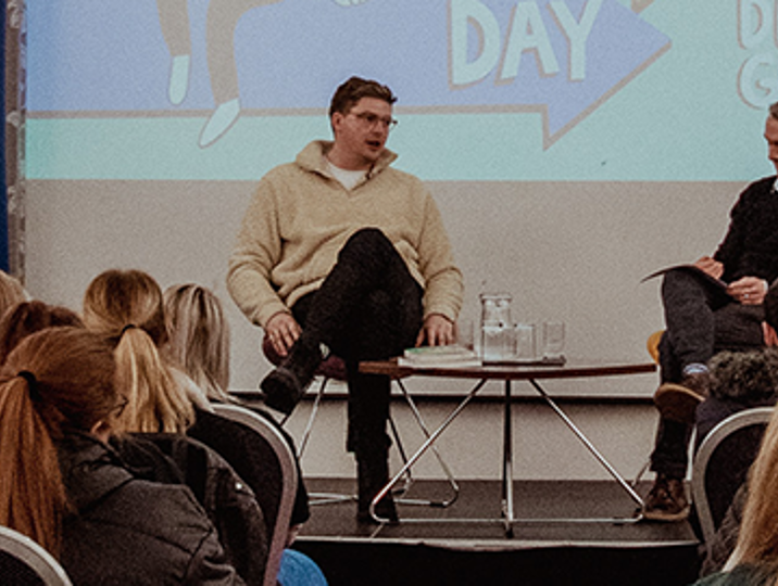 doctor alex george on stage with fife college staff member facing audience of students