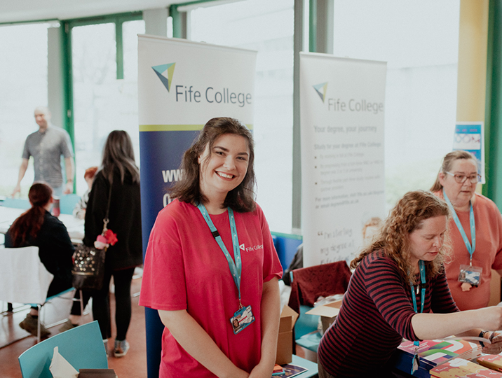 three staff members, one smiling at camera, two talking to students