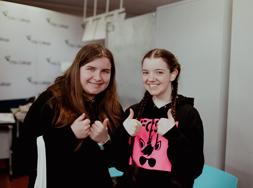 students smiling at camera with thumbs up