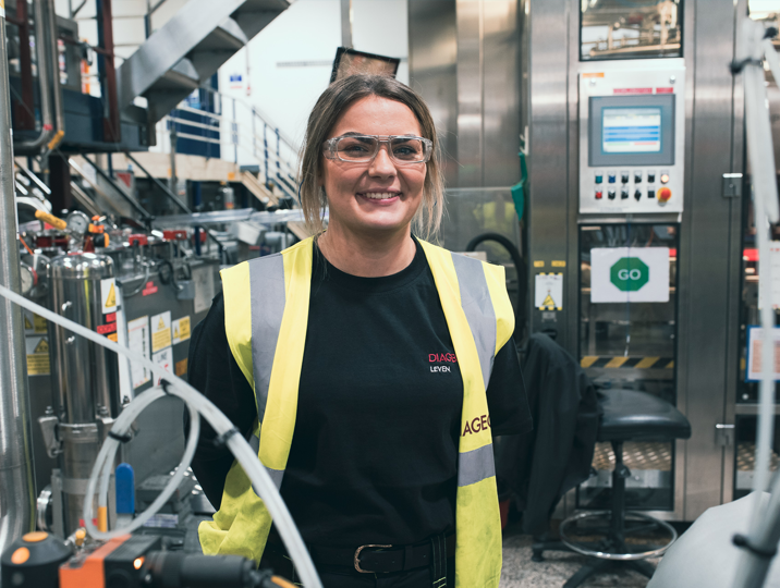 scp female student wearing ppe smiling in front of machinery