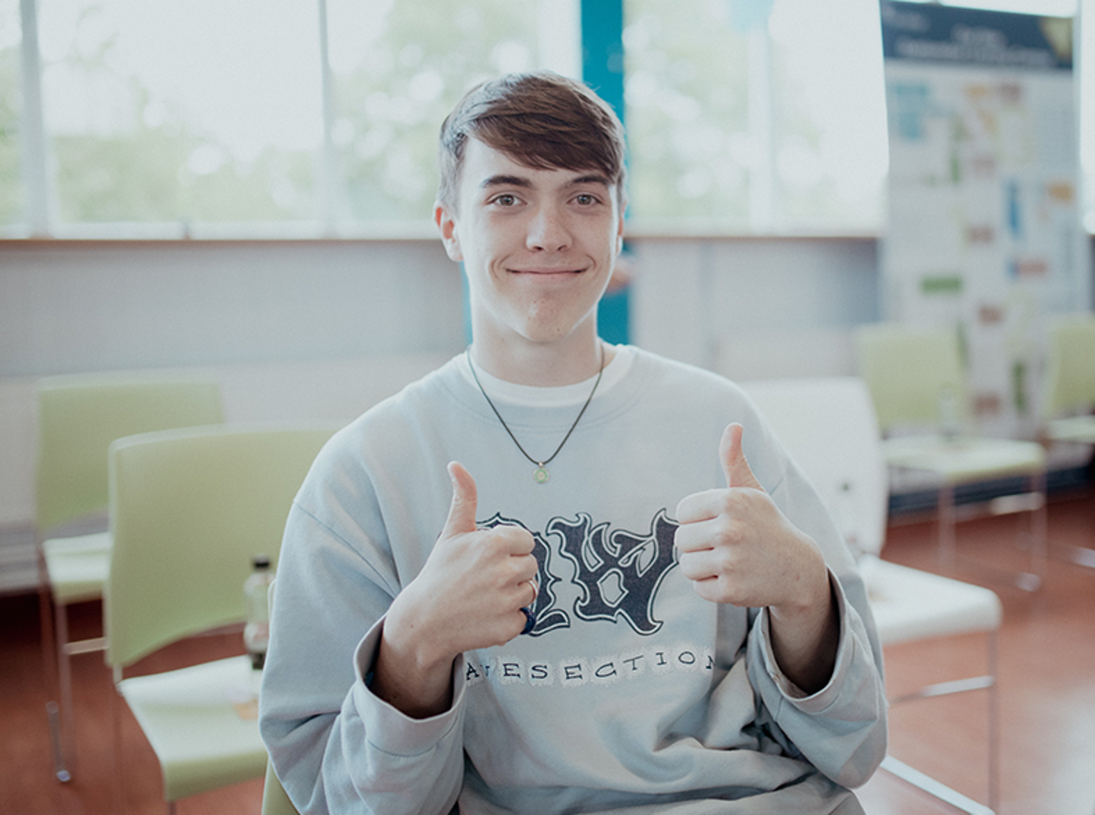 male student smiling at camera with thumbs up
