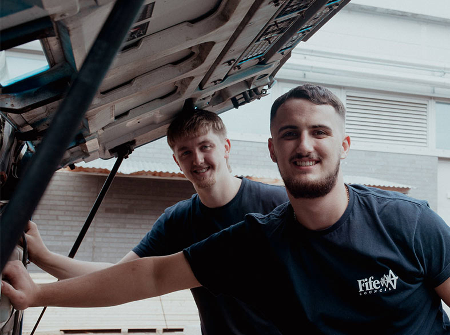 two automotive students next to a HGV