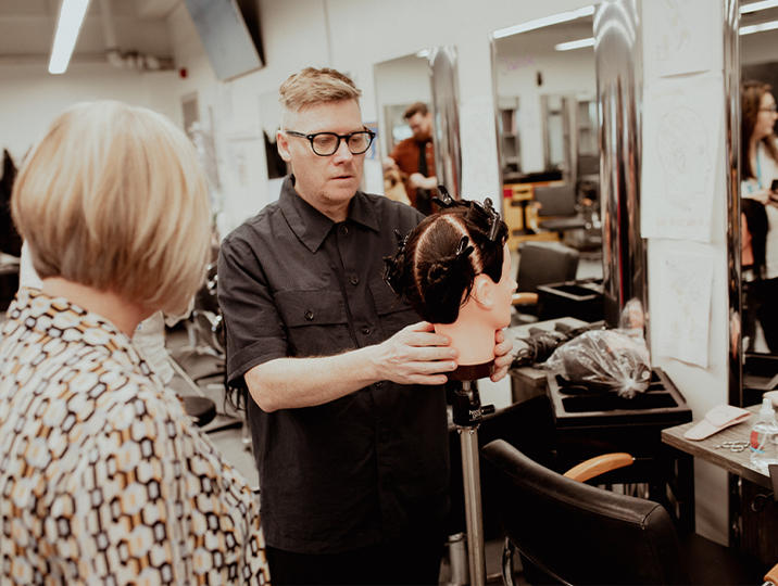 male hairdressing lecturer demonstrating on mannequin