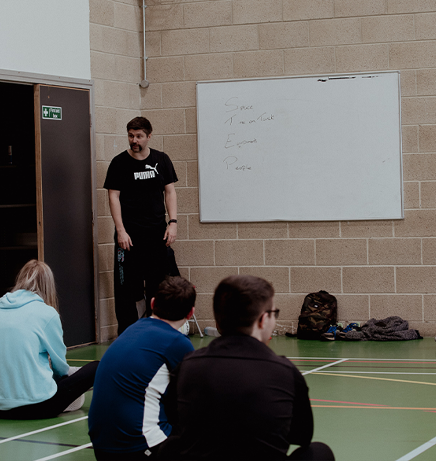 sport lecturer and students in gym hall