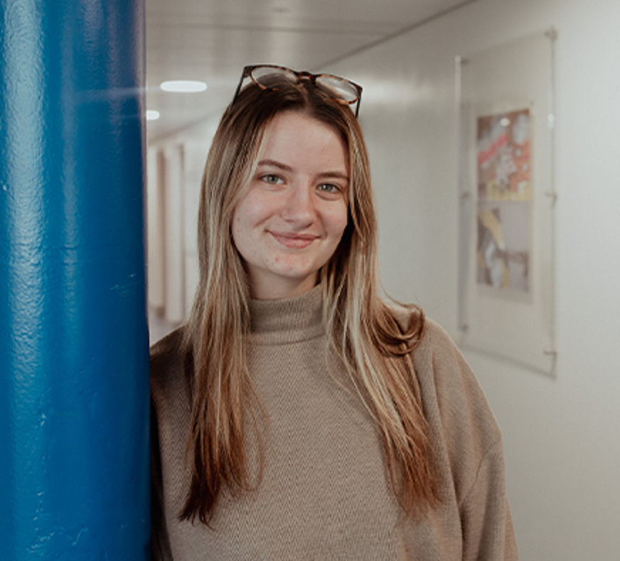 girl leaning on pillar smiling at camera